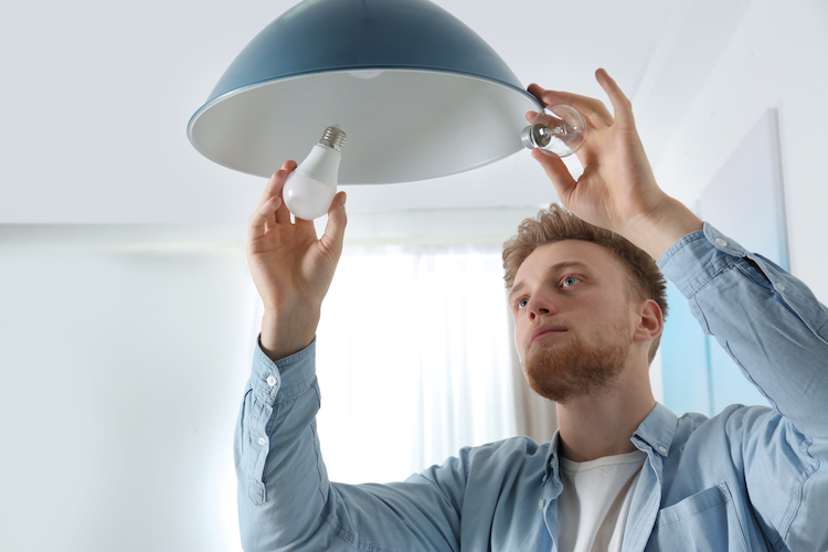 man changing a light bulb on a pendant lamp