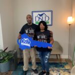 2 people posing holding dsld sign