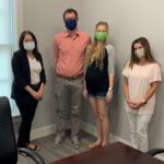 4 people posing for a photo in facemasks
