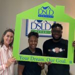 3 people posing holding dsld sign