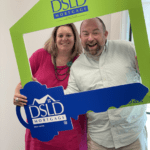 2 people posing holding dsld sign