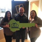 3 people posing for a photo holding a dsld sign