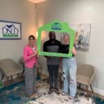 3 people posing holding dsld sign