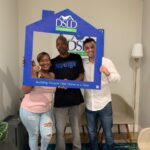 3 people posing holding dsld sign