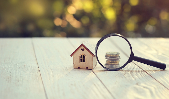 miniature house, money behind a magnifying glass