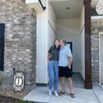 man kissing woman on cheek in front of a house