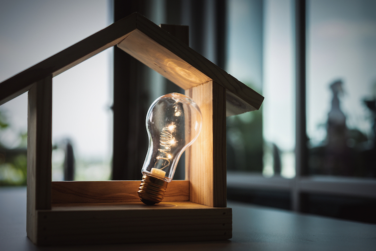 light bulb inside wood house structure on table