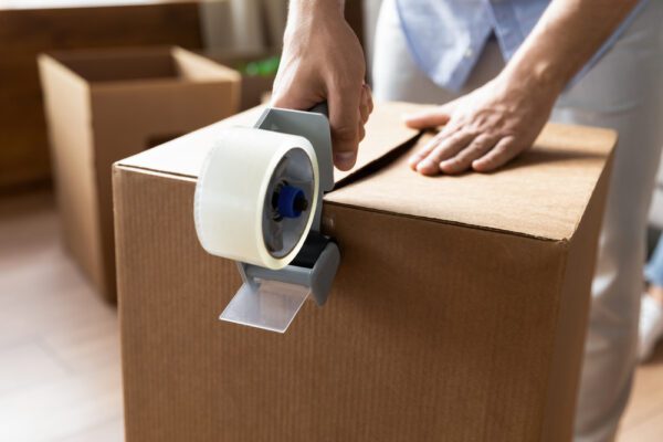 A personal taping up a moving box as part of their moving day checklist